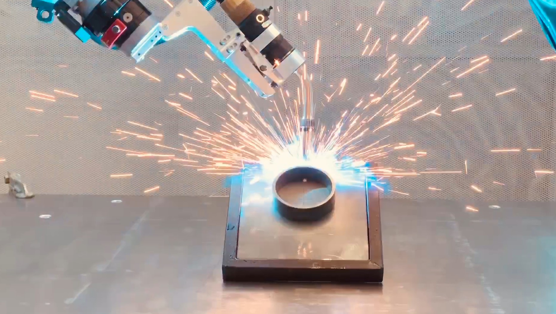 Maucher CNC robot cell welding: path-controlled robot joins a component, sparks at the weld point